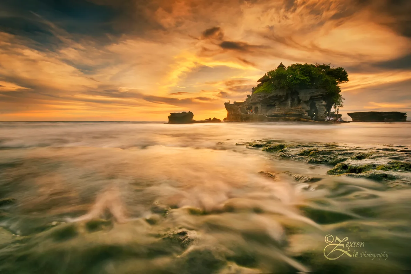 Tanah Lot on its rock as the tide runs out at sunset, Bali