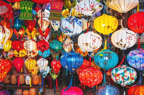 A wall of silk lanterns in every colour, ribbed frames and painted blossom patterns lit from within
