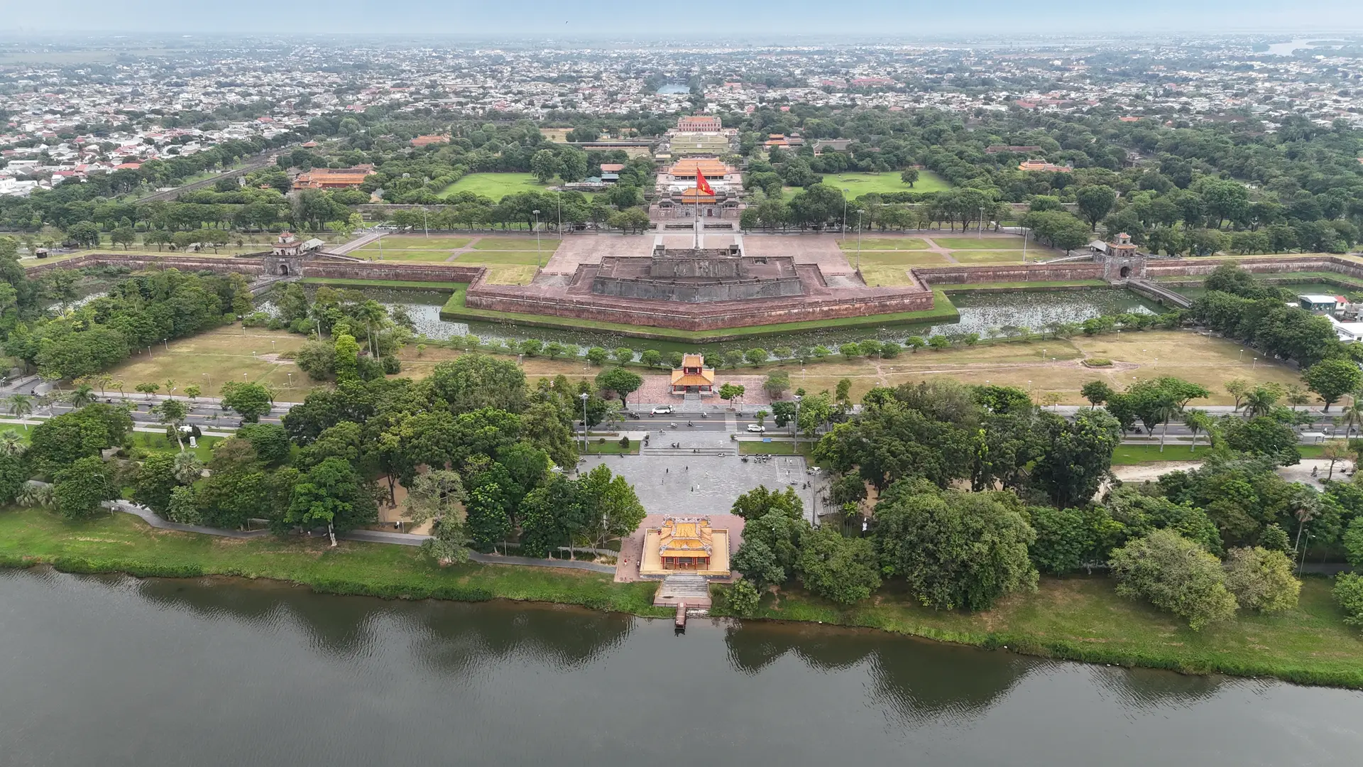 空中俯瞰有围墙的皇城,护城河、旗台和瓦顶城门在树木间展开