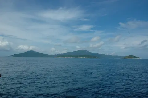 The Cham Islands as a low green ridge on the horizon across open sea under a pale sky