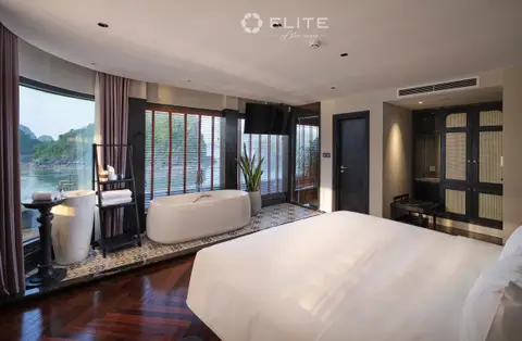 Freestanding bath beside the bed in an Executive suite, with the bay through the corner glass