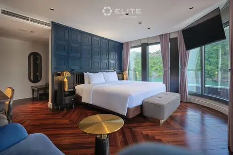 Executive suite bed with a green bench and a curved sofa in the seating area beyond
