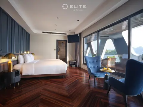 Junior Premium cabin with a double bed and blue armchairs facing a wall of windows
