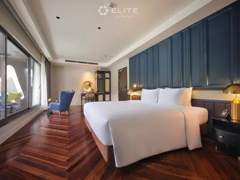 Junior Premium cabin seen lengthways, with the bed, a desk and a seating corner by the glass