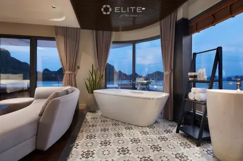 Freestanding bath in the President suite on patterned tiles facing a karst through tall glass