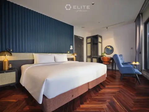 Senior Premium cabin with a double bed against a navy panelled wall and blue armchairs at the window
