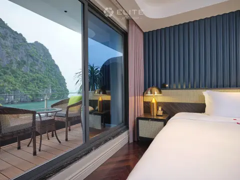 Open sliding door of a Senior cabin onto a private balcony with a table, chairs and a karst behind