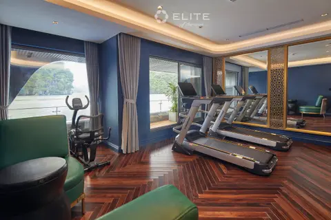 Gym with treadmills and an exercise bike on wood flooring beside a window onto the bay