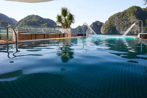 Tiled infinity pool on the top deck with fountain jets and karsts directly beyond the edge