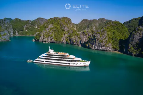 Aerial view of the ship in a green channel between steep wooded limestone islands