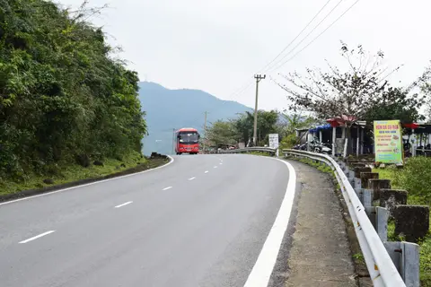 A bus climbing the crash-barriered mountain road of the pass between forested slopes