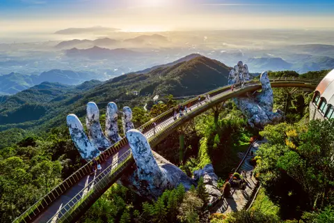 The Golden Bridge held between two giant stone hands, mountains stacked into the haze behind