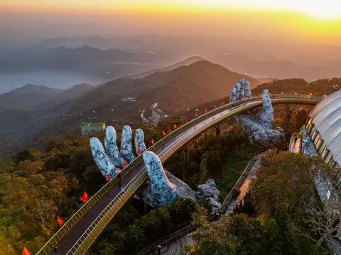 The gold walkway curving above the ridge at sunset, small red flags lining the rail