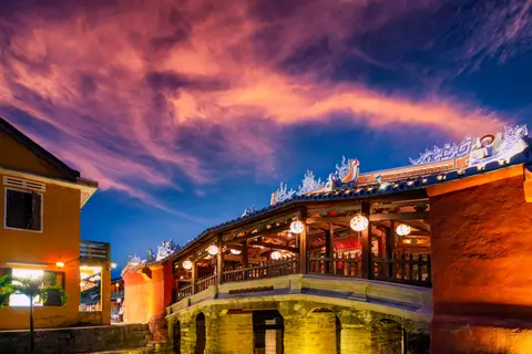 The Japanese Covered Bridge lit from inside at dusk against a deep blue and pink sky