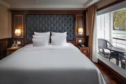 Каюта Deluxe Balcony: двуспальная кровать с мягким изголовьем, темные деревянные панели и окно на бухту