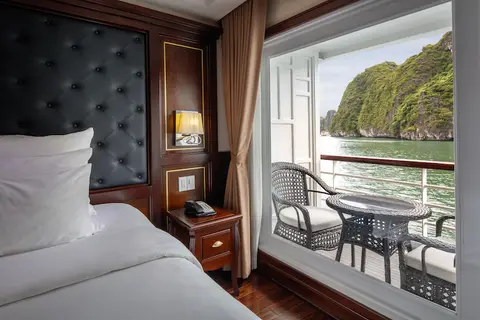 Балкон каюты Deluxe Balcony с плетеным креслом, в дверном проеме — известняковые острова