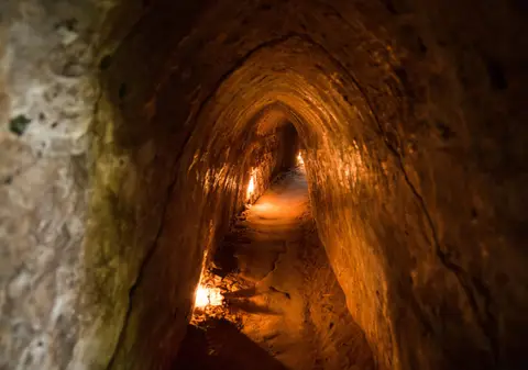 Der schmale Erdgang eines Cu-Chi-Tunnels, der sich im schwachen Licht windet