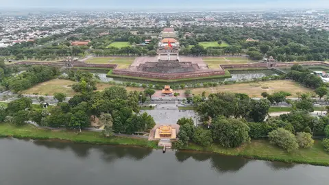 空中俯瞰有围墙的皇城，护城河、旗台和瓦顶城门在树木间展开