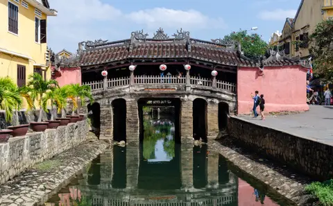 日式廊桥横跨狭窄运河，深色木梁倒映在静水中